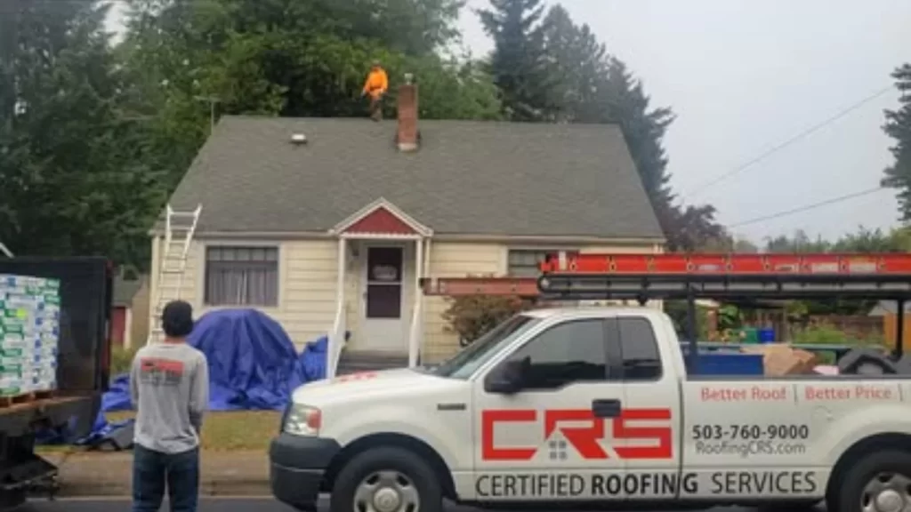 A team from Certified Roofing Services, a roofing company in Portland, is hard at work on a residential roof replacement, with their branded truck parked in front.