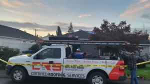 A Certified Roofing Services truck parked at a residential job site at dusk, with caution tape around the work area and a roofer visible on the house.