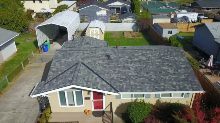 Aerial view of a tan house with a new gray architectural shingle roof in a suburban setting.